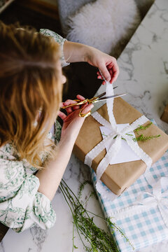 Woman wrapping rustic gift with ribbon