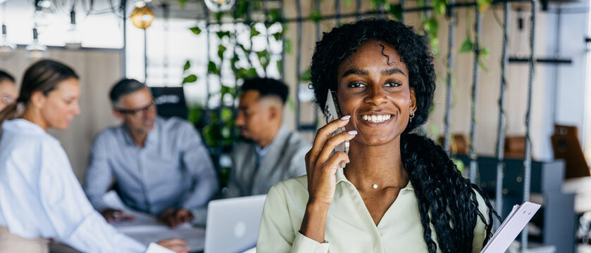 Employee speaking on phone while organizing team meeting schedule