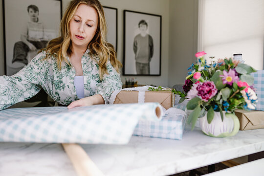 Woman wrapping gifts in bright home workspace