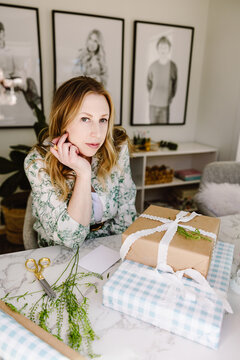 Woman wrapping gifts at home workspace
