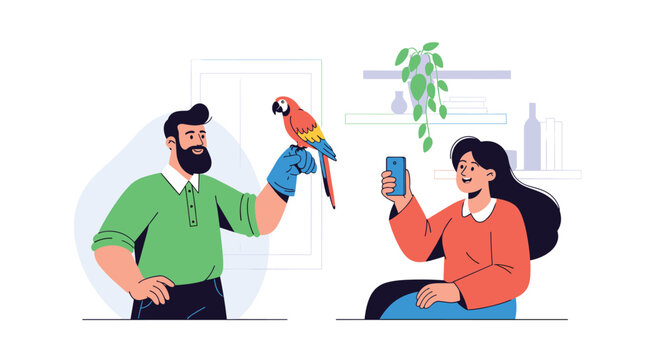 Happy man holding a colorful parrot on a gloved hand while a woman sits nearby and captures the moment on her smartphone camera.