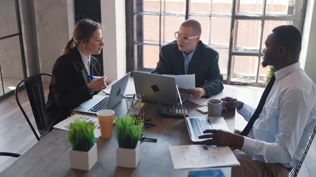 Co-working area in office, three workers communication and talking about work. Modern people in contemporary business center, teamwork in meeting room, marketing, financial and economics professionals