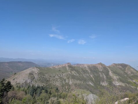 Ripresa panoramica di una cresta montuosa con rocce affioranti e pendii erbosi illuminati dal cielo limpido, in un paesaggio naturale incontaminato