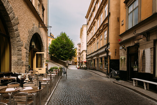 Stone arch passage and outdoor cafe in Gamla Stan, Stockholm, Sweden. Narrow cobblestone street lined with colorful historic buildings and shops in Gamla Stan, Stockholm's old town.