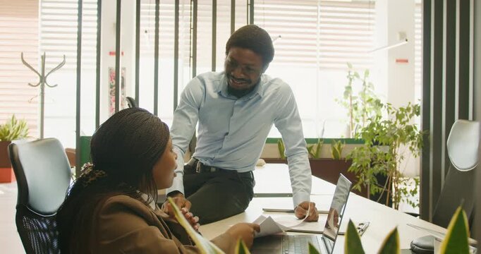 Supportive mentor guides colleague amid bright workspace environment