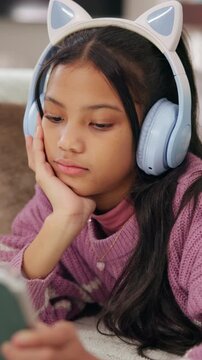 Streaming, headphones or kid on floor with tablet, movie binge or cartoon watching on digital app. Relax, multimedia or girl in home with tech, child series or subscription on entertainment platform