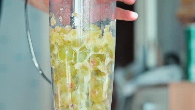 Fresh green grapes are placed in a blender for making a smoothie. The blending process starts, transforming the grapes into a smooth mixture ready for consumption