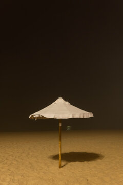Minimalist night scene of a deserted beach with a white umbrella