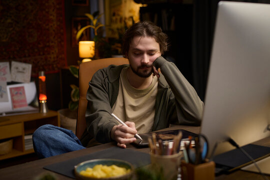 Digital artist drawing on tablet at home workspace at night