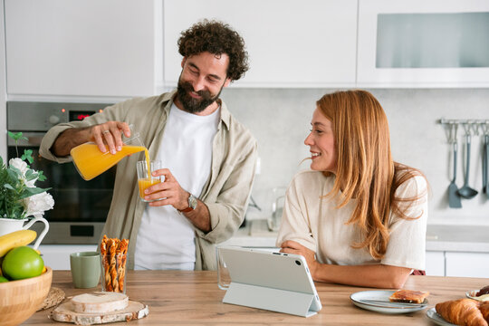Couple having breakfast in kitchen while using digital tablet in morning