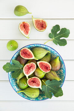 Fresh halved and whole figs in a bowl on a white table