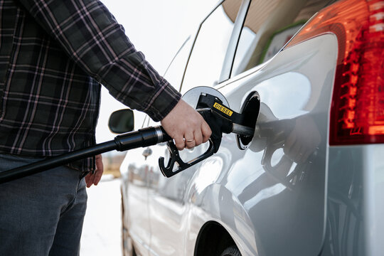 Hand holding diesel nozzle refilling car at gas station
