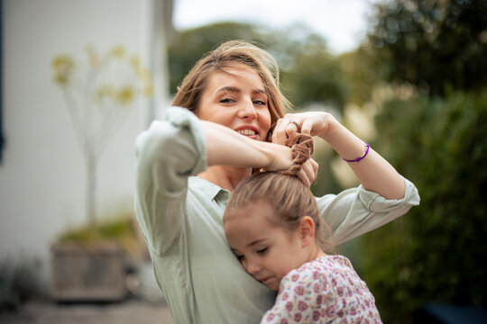 Smiling woman tying hair of daughter with scrunchie