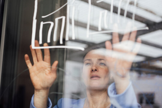 Businesswoman examining graph on glass planning strategy in office