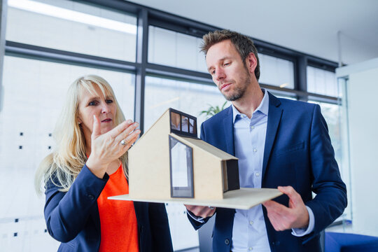 Architects discussing over model house in office