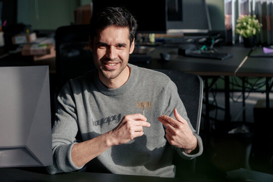 Happy mature businessman holding prop and gesturing at desk