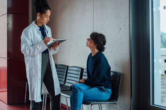 Doctor discussing with patient sitting on chair in hospital