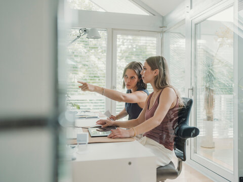 Two colleagues collaborating in a bright home office workspace