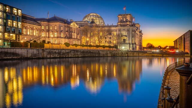 Illuminated Reichstag building reflecting in Spree river at dusk