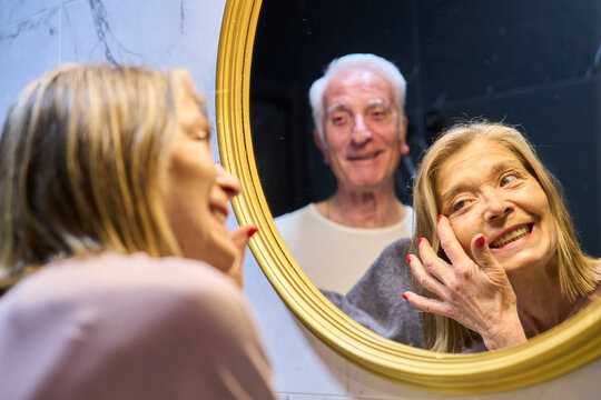 Couple looking at reflection in bathroom mirror for skin care