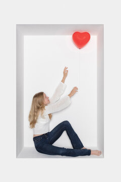 Teenage girl with heart shape balloon sitting in alcove