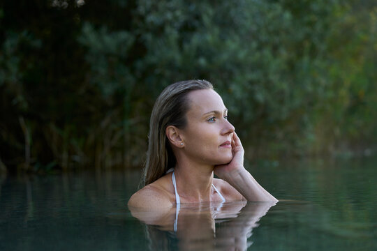Woman in water outdoors with serene expression and natural beauty