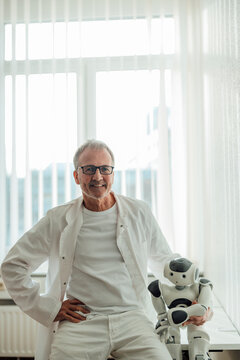 Smiling doctor sitting with a humanoid robot indoors