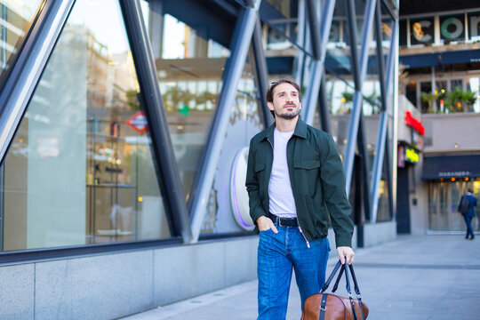Commuter walking down an urban street holding a travel bag