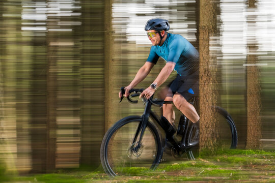 Cyclist gravel biking fast through a forest trail in Remstal valley
