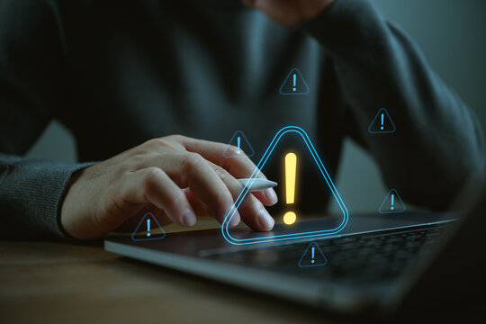 Person using laptop with warning alert icons and system notification, representing cybersecurity risk, data protection issues, human error and digital threat in online technology environment