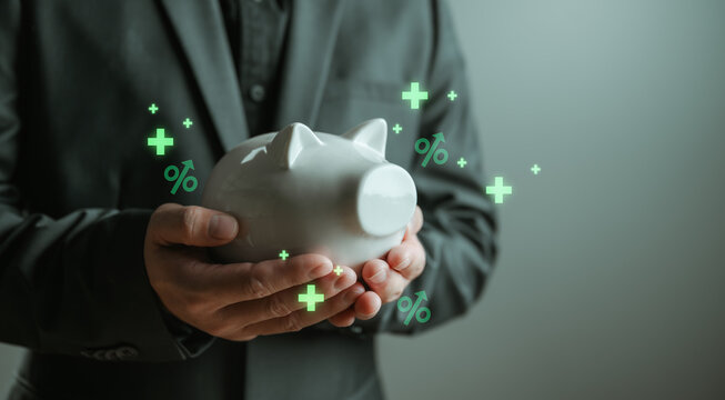 Businessman holding piggy bank with financial icons showing interest rate, savings growth and investment return, representing personal finance planning, wealth management and passive income concept