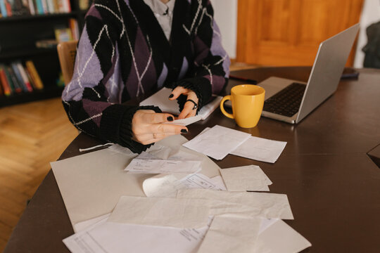 Calculating expenses and reviewing receipts with laptop on desk