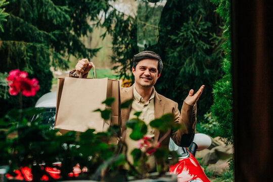 Smiling shopper arriving at suburban home with shopping bags
