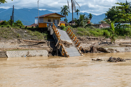 Collapsed small bridge over muddy river after flash flood in Padang, West Sumatra, Indonesia, showing infrastructure damage, disaster impact, and environmental crisis in tropical area