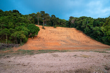 Large deforested area surrounded by hill with green tropical rainforest in Asia, jungles in Thailand and Vietnam destroyed by local erosion and human impact for economical agricultural development. © DimaBerlin