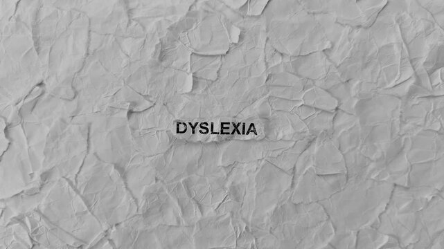 Crumpled piece of paper with word Dyslexia on torn crumpled white paper pieces background. Zoom in