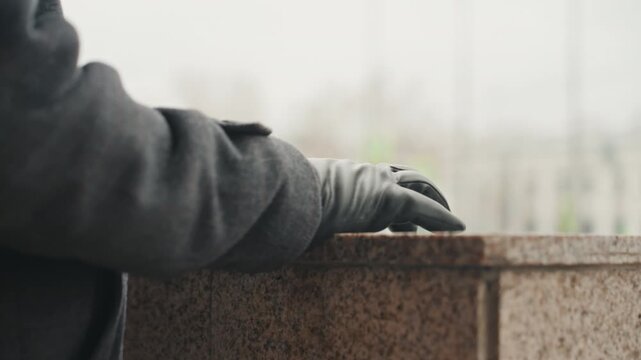 Creator designer testing granite ledge outdoors, closeup of gloved hand reaching to stone surface, exploring texture and moisture, cautious gesture on polished edge, urban plaza in soft focus,