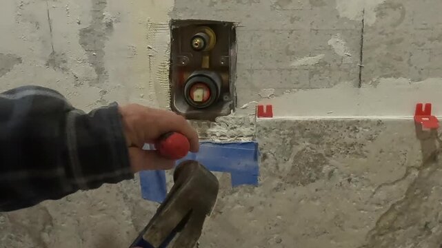 Women chiseling tile around shower diverter 4