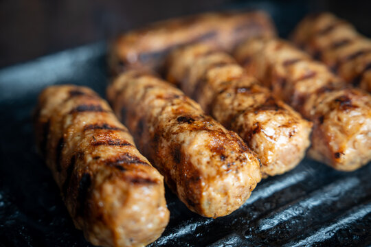 Grilling sausages on a metal tray during a sunny afternoon in a backyard gathering with family and friends