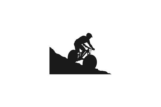 Mountain biker silhouette riding a bicycle down a steep rocky hill