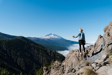 Obraz premium Tourist standing on mountain admiring breathtaking view of volcano Teide, Tenerife, Canary, Spain.