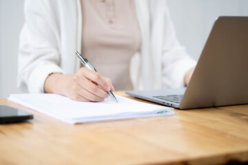 Fototapeta premium Close Up of Female Professional Writing Notes with Laptop