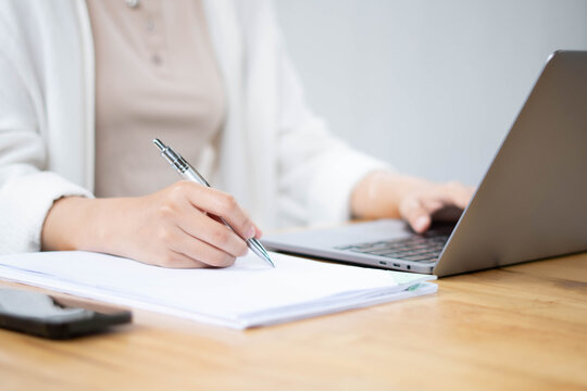 Close Up of Female Professional Writing Notes with Laptop