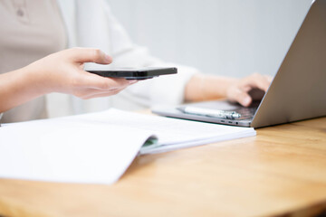 Fototapeta premium Businesswoman Using Smartphone While Reviewing Documents at Desk
