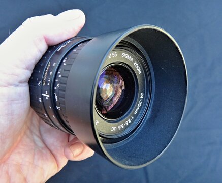 Hand holding Sigma zoom camera lens with hood