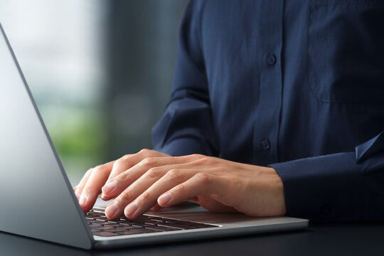 Businessman using laptop computer at desk in office. Closeup of hands and keyboard. Business technologies.