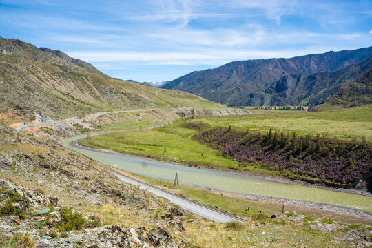 Aerial view of Chuya River flowing between mountains in Chuysky Trakt area Altai Russia. Scenic Siberian river valley surrounded by rugged terrain.
