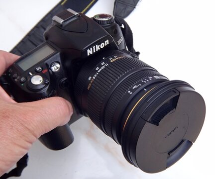 Hand holding Nikon D90 DSLR camera with Sigma lens