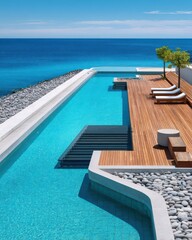 Fototapeta premium Infinity pool overlooking turquoise ocean with wooden deck, lounge chairs and white pebbles