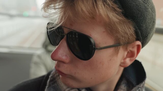 Youthful artist portrait. Closeup of young designer on subway. Focused young creator with reflective window background. Creative young individual captures introspection during city transit ride